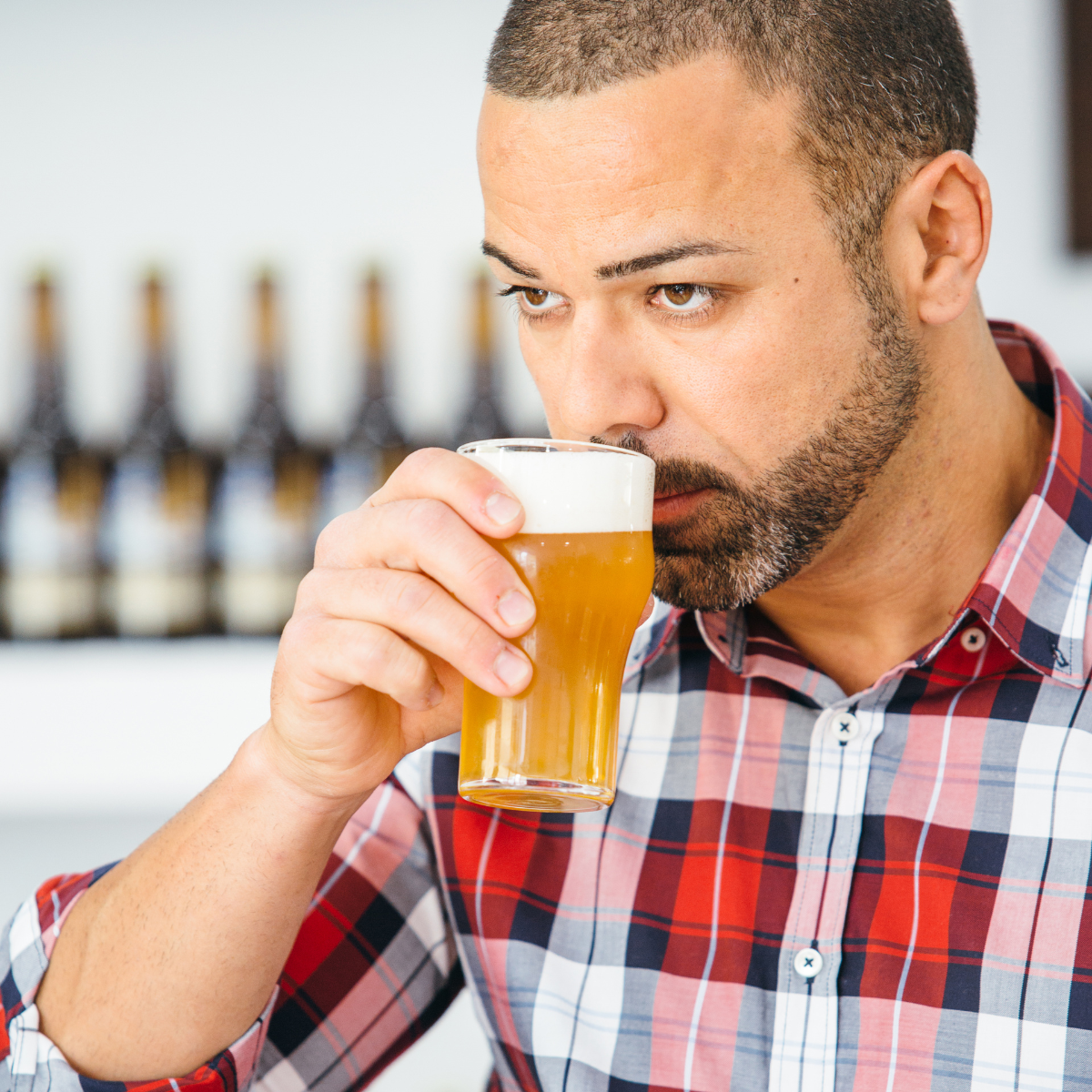 Man in flannel shirt smelling his beer